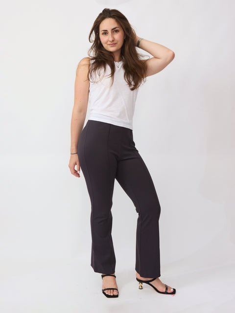Woman wearing a white sleeveless top and black pants on a white background