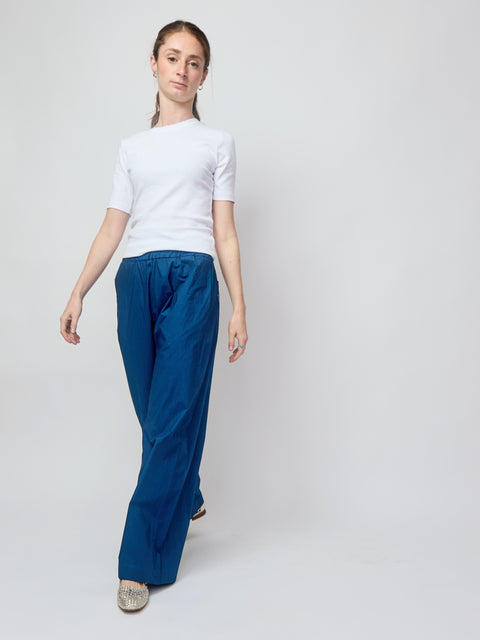 Person wearing a white shirt and blue pants on a plain background