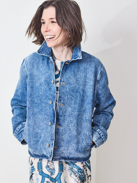 Person wearing a blue denim jacket against a plain background