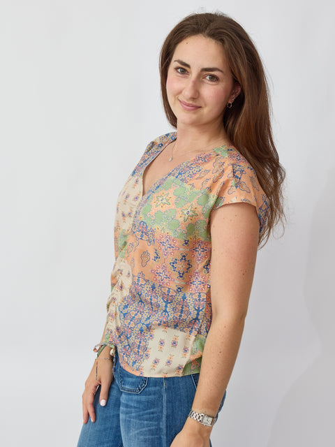 Woman wearing a colorful floral blouse and blue jeans on a white background