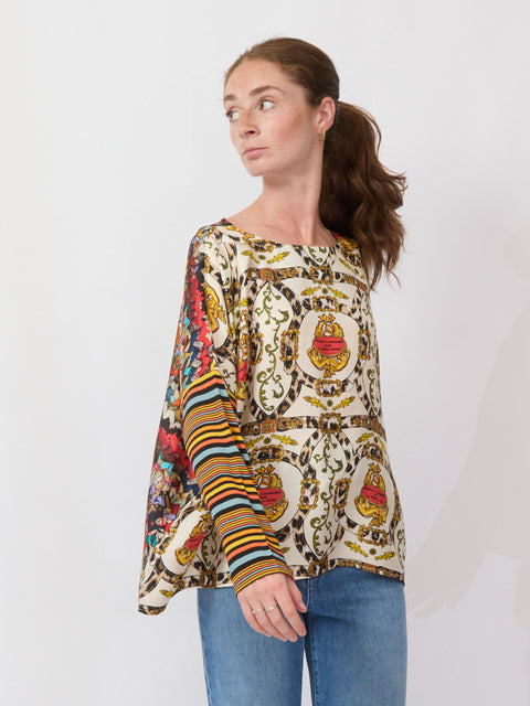 Woman wearing a colorful patterned blouse with a plain background