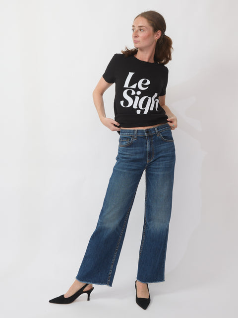 Woman wearing a black t-shirt with 'Le Sigh' text and blue jeans on a white background