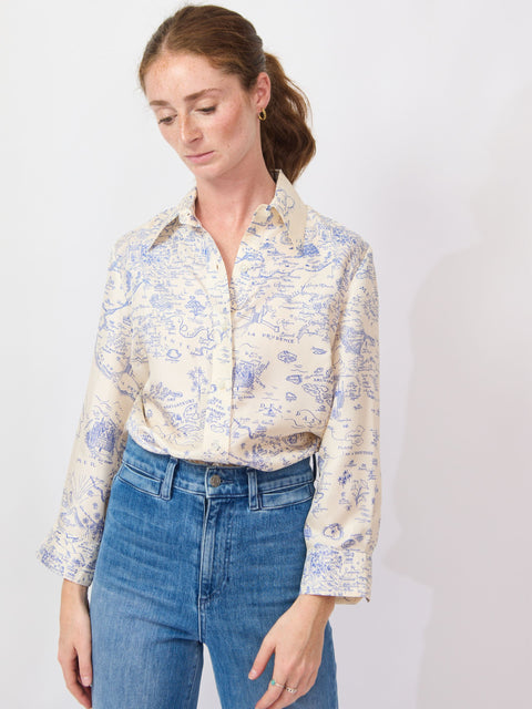 Woman wearing a floral blouse and blue jeans against a white background