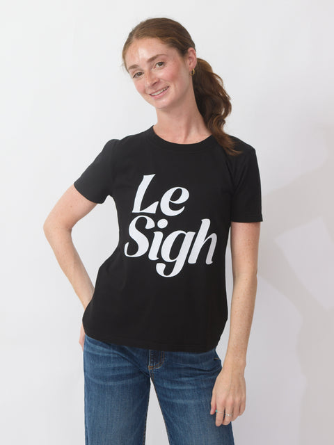 Person wearing a black t-shirt with 'Le Sigh' text on a plain background
