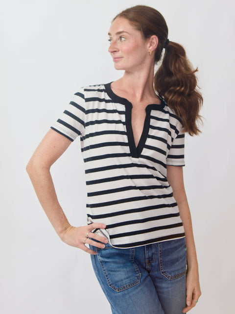 Woman wearing a black and white striped shirt with blue jeans on a plain background