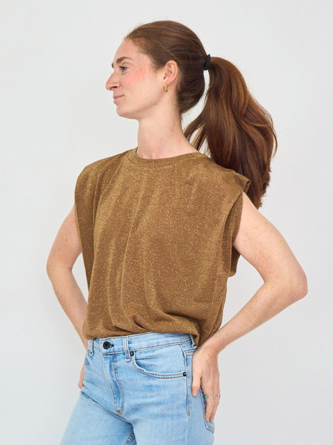 Woman wearing a brown sleeveless top and blue jeans against a white background