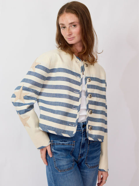 Woman wearing a striped sweater and jeans against a plain background