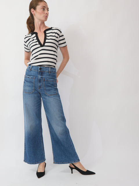 Woman wearing a black and white striped shirt and blue jeans on a white background