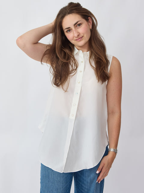 Woman wearing a white sleeveless blouse and blue jeans on a plain background