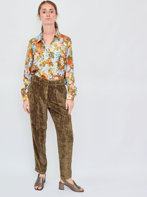 Woman wearing a floral blouse and brown pants on a white background