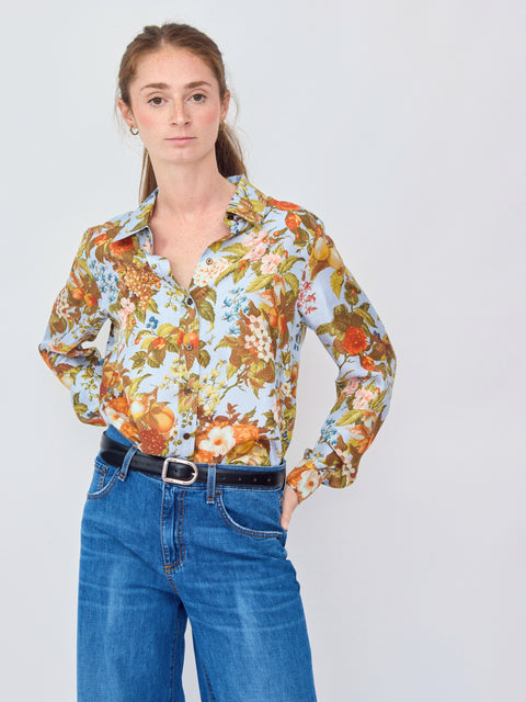 Woman wearing a floral blouse and blue jeans against a plain background