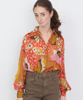 Long-sleeve button-up blouse with vibrant floral print in orange, yellow, and pink tones.