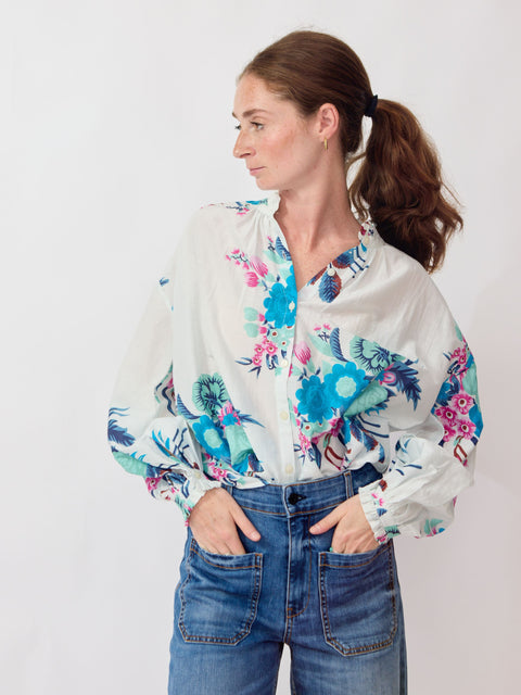 Woman wearing a floral blouse and jeans on a white background