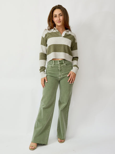 Woman wearing a striped sweater and green pants against a white background
