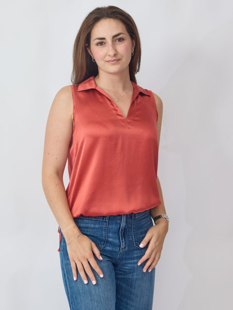 Woman wearing a red sleeveless top and blue jeans against a white background