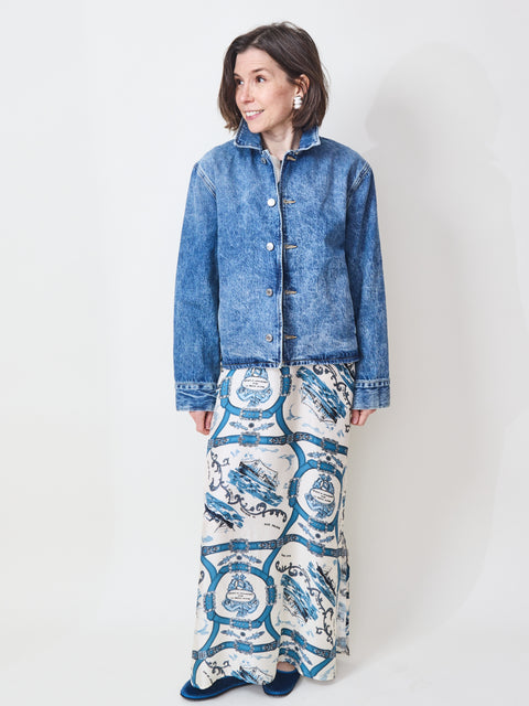 Woman wearing a blue denim jacket and patterned pants on a white background