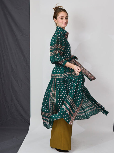 woman twirling in dark green printed silk dress 