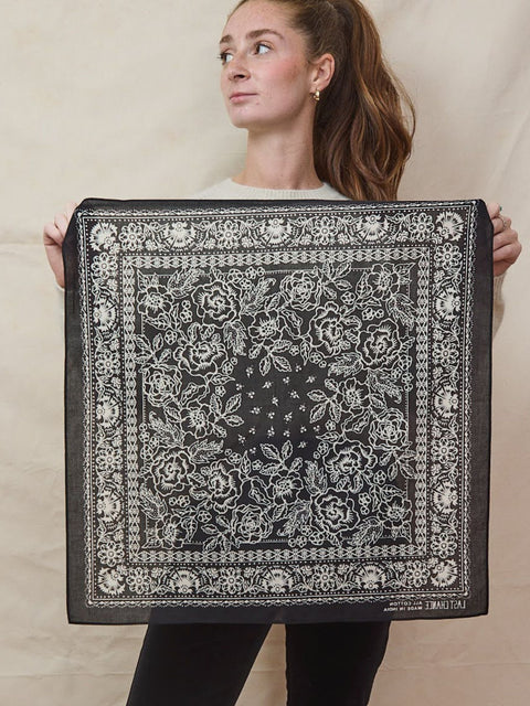 Young lady holds a soft cotton bandana with hand-drawn floral pattern.