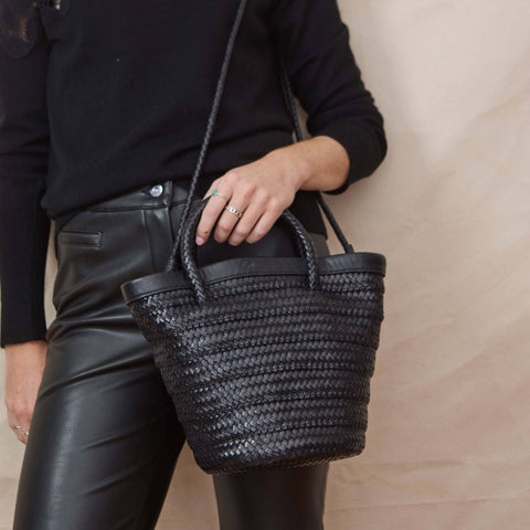 black woven leather bag  next to woman wearing all black