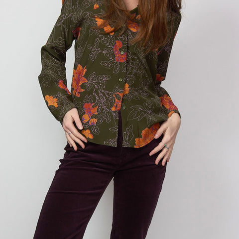 close up shot of woman wearing green printed blouse with burgundy velvet pants