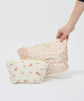 Two fabric pouches with zipper closures; one cream with pink leopard print, the other cream with small pink floral.