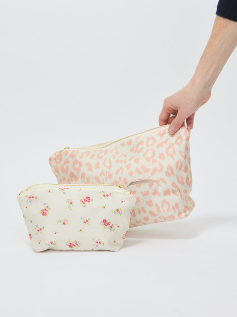 Two fabric pouches with zipper closures; one cream with pink leopard print, the other cream with small pink floral.