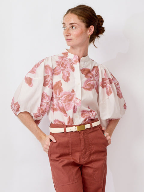 Woman wearing a floral blouse and red pants on a white background
