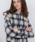 Purple and cream plaid flannel shirt with front button pockets and long sleeves.