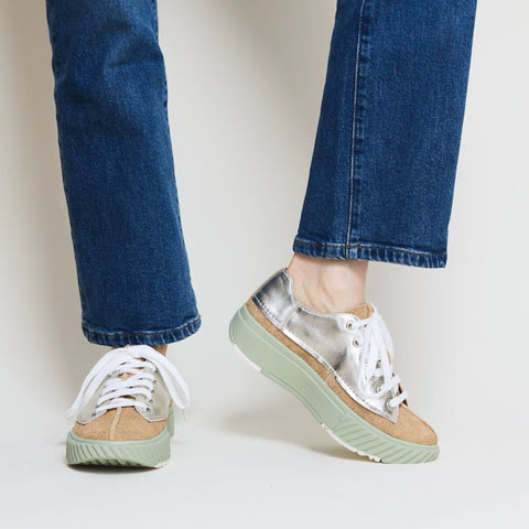 Young lady wears jeans with a pair of platform silver and brown suede sneakers