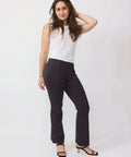 Woman wearing a white sleeveless top and black pants on a white background
