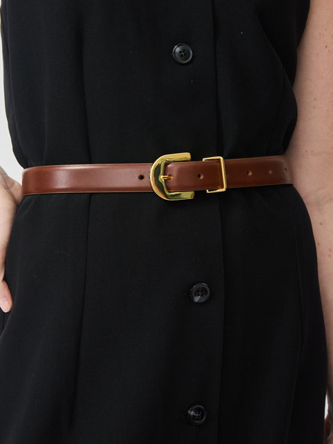 Mahogany leather belt with gold rectangular buckle worn over black buttoned garment.