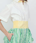 Dress with white short-sleeve top, yellow waistband, and green and white vertical striped skirt with pockets.