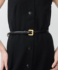 Slim black leather belt with a small shiny gold buckle, worn over a black buttoned dress.