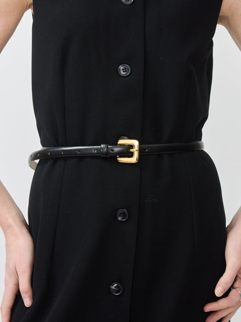 Slim black leather belt with a small shiny gold buckle, worn over a black buttoned dress.