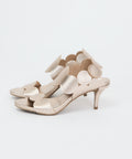 Beige textured heels with scalloped ankle strap and circular embellishments, open toe design.