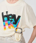 Cream-colored cotton t-shirt with colorful "hey" graphic and cream fabric belt with silver buckle.