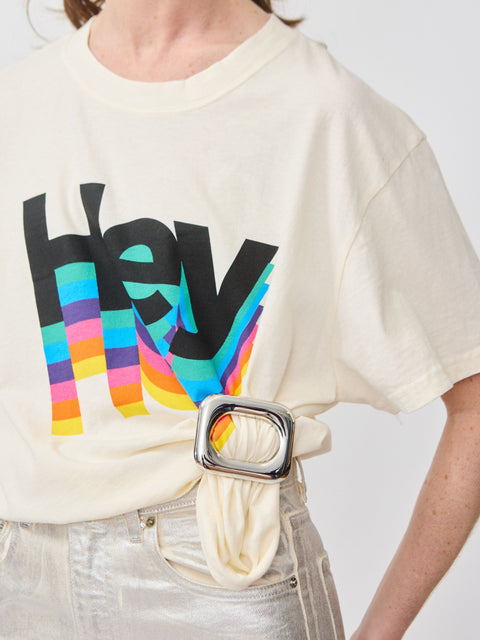 Cream-colored cotton t-shirt with colorful "hey" graphic and cream fabric belt with silver buckle.