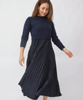 Woman wearing a navy blue sweater and skirt on a white background