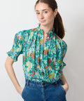 Woman wearing a colorful floral blouse with a plain background