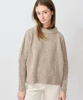 Light beige chunky knit sweater with high relaxed turtleneck and dropped shoulders.