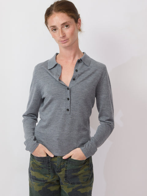 Woman wearing a gray long-sleeve shirt with buttons and camouflage pants on a white background