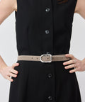 Grey suede belt with silver buckle worn over black button-up dress.