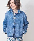 Person wearing a blue denim jacket against a plain background
