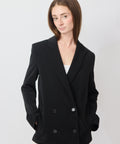Black double-breasted blazer with notch lapels, worn over a white top.