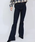 High-waisted indigo denim jeans with a flared leg and classic five-pocket design, worn with a plaid shirt and black pointed.