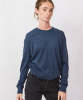 Person wearing a blue sweater and black pants on a white background