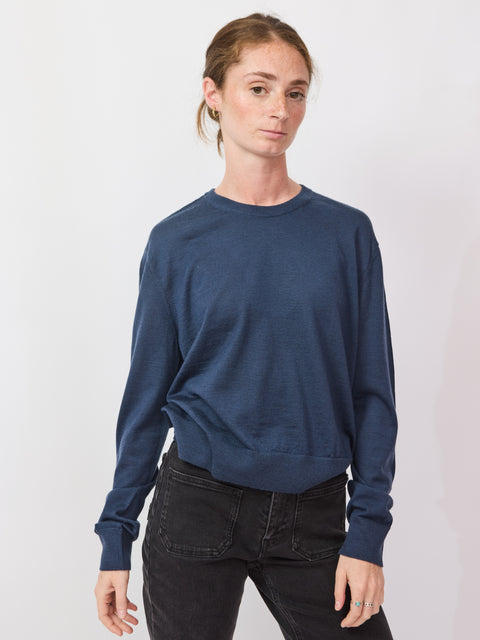 Person wearing a blue sweater and black pants on a white background