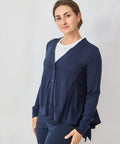 Woman wearing a navy blue cardigan over a white shirt on a light gray background