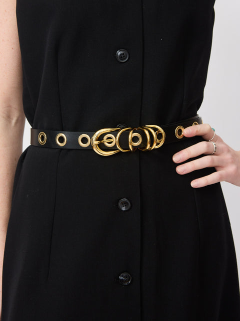 Black leather belt with gold double-ring buckle and gold rivet accents worn over a black dress.