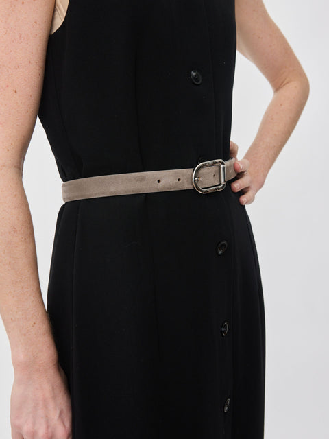 Grey suede belt with silver rounded buckle worn over black dress.